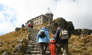 Rodzina wspina się kamiennymi schodami na Kasprowy Wierch. W tle budynek obserwatorium.