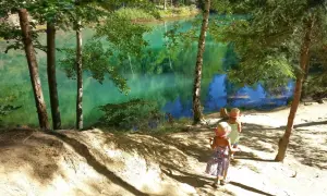 Dwie dziewczynki w słomkowych kapeluszach idą ścieżką nad turkusowe jezioro. Idealne miejsce, gdzie w góry z dziećmi.