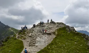 Grupa turystów na kamienistym szlaku górskim pod Kasprowym Wierchem.