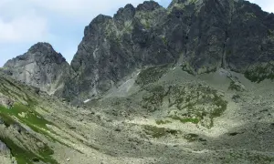 Kamieniste zbocza i skaliste szczyty górskie, gdzie widać ślady szlaków. Kozi Wierch w oddali.