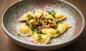 Pierogi z boczkiem i cebulką, danie z restauracji Bacówka, prezentowane na talerzu.