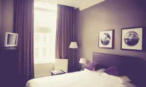 Pokój hotelowy z łóżkiem, oknem i telewizorem.