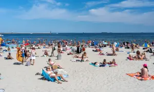 Tłum ludzi na plaży, opalanie, kąpiel w morzu. Zastanawiasz się, ile kosztuje nocleg nad morzem?