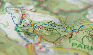 Mapa turystyczna z zaznaczonymi szlakami. Kolory szlaków oznaczają różne trasy piesze i rowerowe, pomagając w nawigacji.