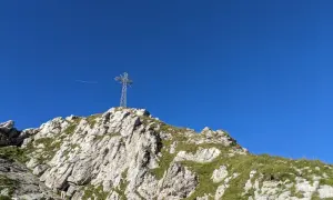 Krzyż na szczycie skalistego Giewontu na tle błękitnego nieba.