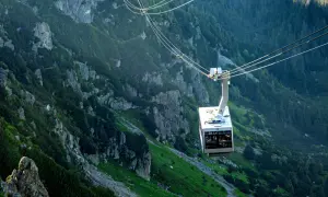 Kolejka linowa w Tatrach na tle skalistych zboczy i lasu.