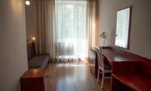 Pokój hotelowy z kanapą, biurkiem i lustrem. Zastanawiasz się, ile kosztuje nocleg w Zakopanem?