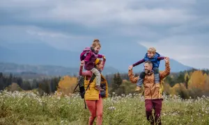 Rodzina na szlaku w górach jesienią, dzieci na ramionach rodziców.