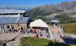 Ludzie odpoczywają przy górnej stacji kolejki linowej na Kasprowy Wierch. W tle piękne Tatry.