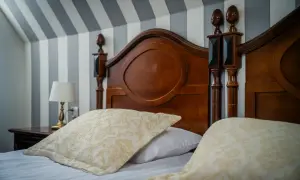 Przytulne łóżko z ozdobnymi poduszkami i drewnianym zagłówkiem. Idealne miejsce na nocleg, zastanawiasz się, ile wynosi ryczałt za nocleg?