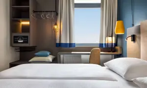 Nowoczesny pokój hotelowy z wygodnym łóżkiem, biurkiem i oknem. Zastanawiasz się, ile kosztuje nocleg w Krakowie?