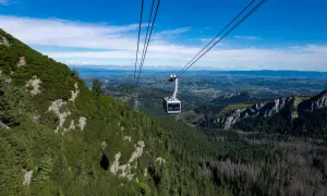 Kolejka linowa PKL Kasprowy Wierch wjeżdża na zbocze górskie porośnięte kosodrzewiną, z widokiem na dolinę.
