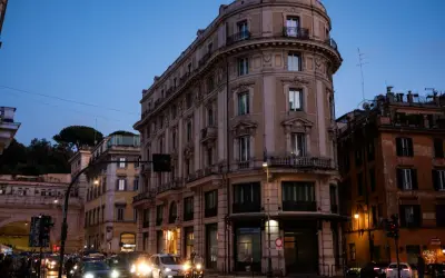 Wieczorny Rzym, ruchliwe skrzyżowanie. Zastanawiasz się, gdzie najlepiej nocleg w Rzymie? To miasto oferuje wiele opcji.