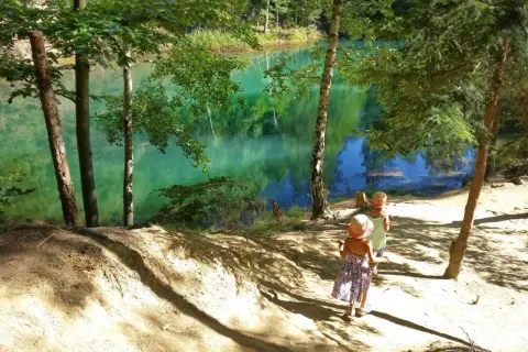 Dwie dziewczynki w słomkowych kapeluszach idą ścieżką nad turkusowe jezioro. Idealne miejsce, gdzie w góry z dziećmi.