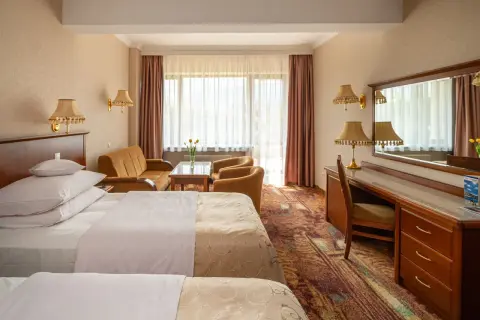 Pokój hotelowy z dwoma łóżkami, kanapą i biurkiem. Dowiedz się, ile kosztuje nocleg w hotelu Gołębiewski.