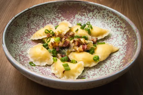 Pierogi z boczkiem i cebulką, danie z restauracji Bacówka, prezentowane na talerzu.