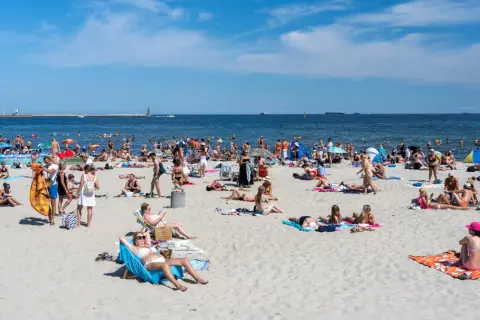 Tłum ludzi na plaży, opalanie, kąpiel w morzu. Zastanawiasz się, ile kosztuje nocleg nad morzem?