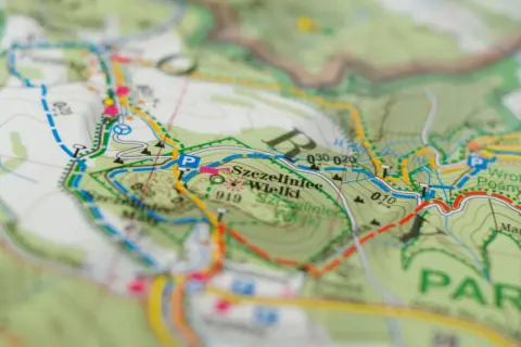 Mapa turystyczna z zaznaczonymi szlakami. Kolory szlaków oznaczają różne trasy piesze i rowerowe, pomagając w nawigacji.
