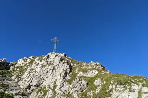 Krzyż na szczycie skalistego Giewontu na tle błękitnego nieba.