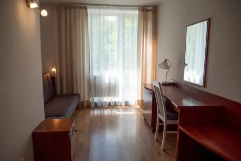 Pokój hotelowy z kanapą, biurkiem i lustrem. Zastanawiasz się, ile kosztuje nocleg w Zakopanem?