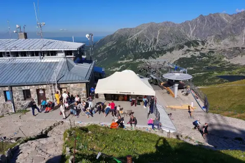 Ludzie odpoczywają przy górnej stacji kolejki linowej na Kasprowy Wierch. W tle piękne Tatry.
