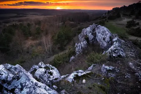 Zachód słońca nad Górami Świętokrzyskimi. Skaliste szczyty i lasy tworzą malowniczy krajobraz. Idealne miejsce, by zobaczyć piękno polskiej przyrody.