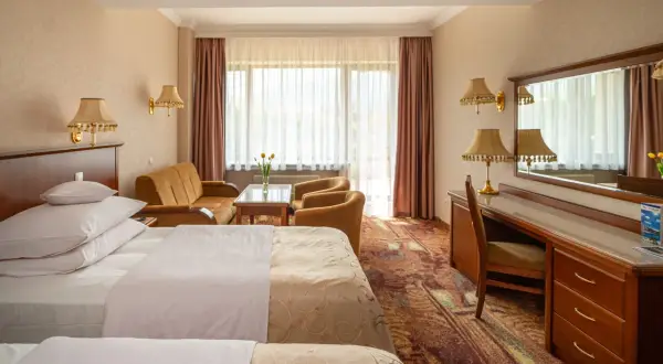 Pokój hotelowy z dwoma łóżkami, kanapą i biurkiem. Dowiedz się, ile kosztuje nocleg w hotelu Gołębiewski.