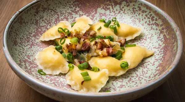 Pierogi z boczkiem i cebulką, danie z restauracji Bacówka, prezentowane na talerzu.
