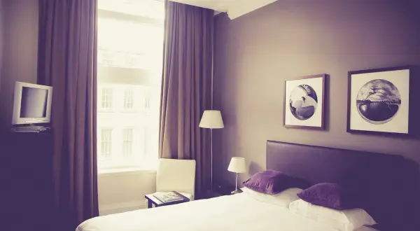 Pokój hotelowy z łóżkiem, oknem i telewizorem.