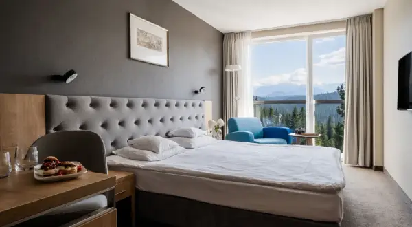 Pokój w hotelu Harnaś Wierch, Bukowina Tatrzańska. Wygodne łóżko, fotel i widok na góry.
