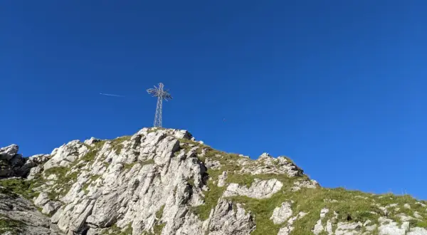 Krzyż na szczycie skalistego Giewontu na tle błękitnego nieba.