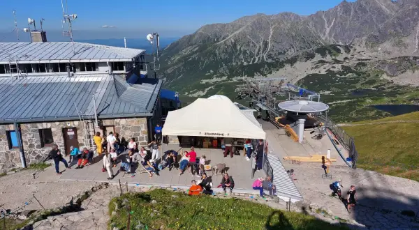Ludzie odpoczywają przy górnej stacji kolejki linowej na Kasprowy Wierch. W tle piękne Tatry.