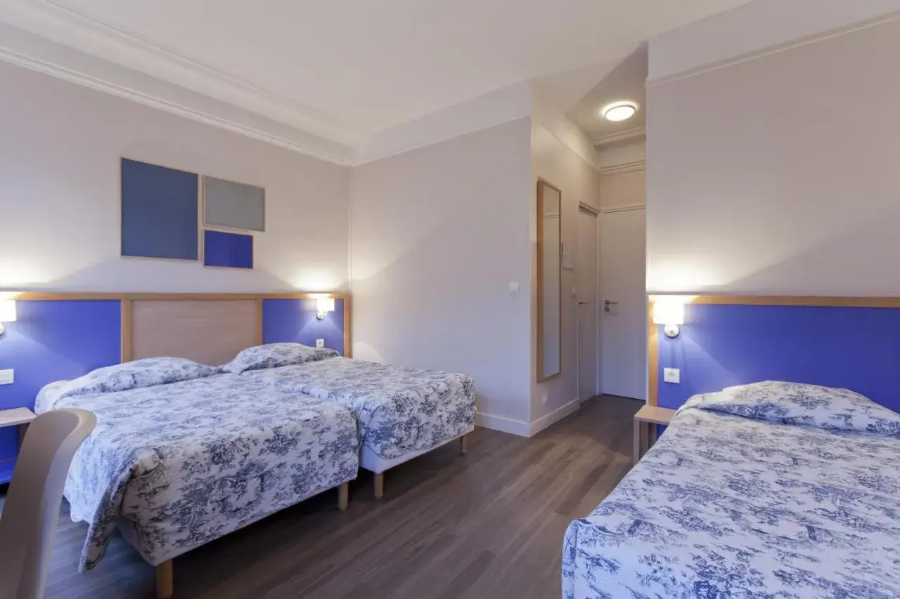 Pok&oacute;j hotelowy z trzema ł&oacute;żkami, idealny na nocleg w Paryżu. Wygodne, przytulne wnętrze z niebieskimi akcentami.