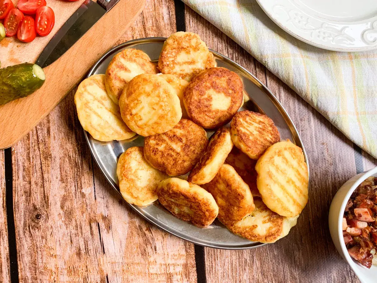 Placki ziemniaczane na talerzu, idealne do restauracji bacówka menu. Obok pomidorki, ogórek i miseczka z dodatkami.