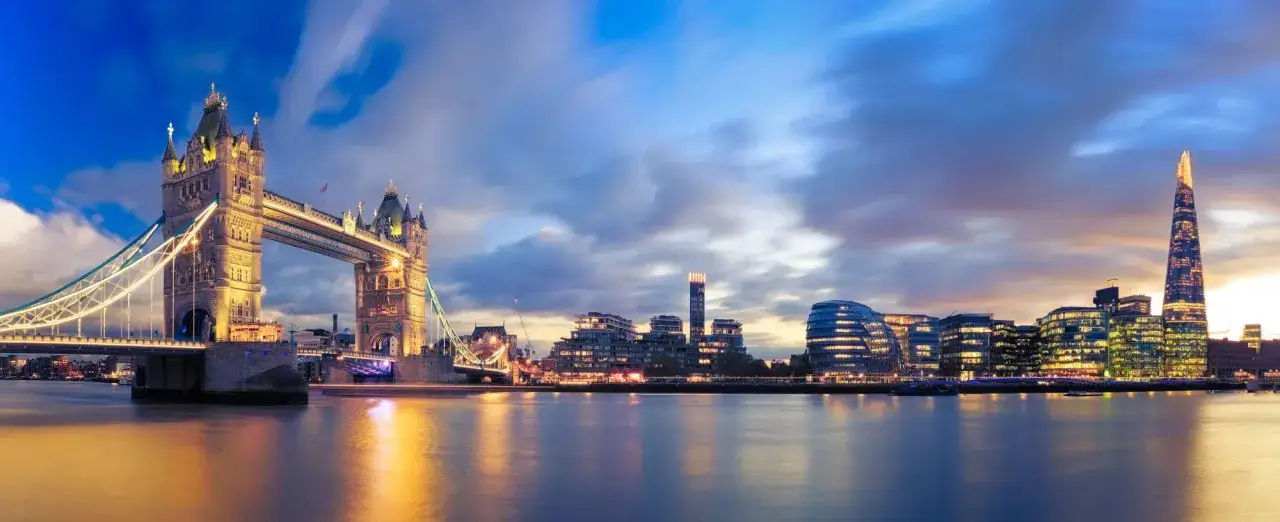 Wieczorny widok na Tower Bridge i nowoczesne budynki Londynu. Zastanawiasz się, ile kosztuje nocleg w Londynie?