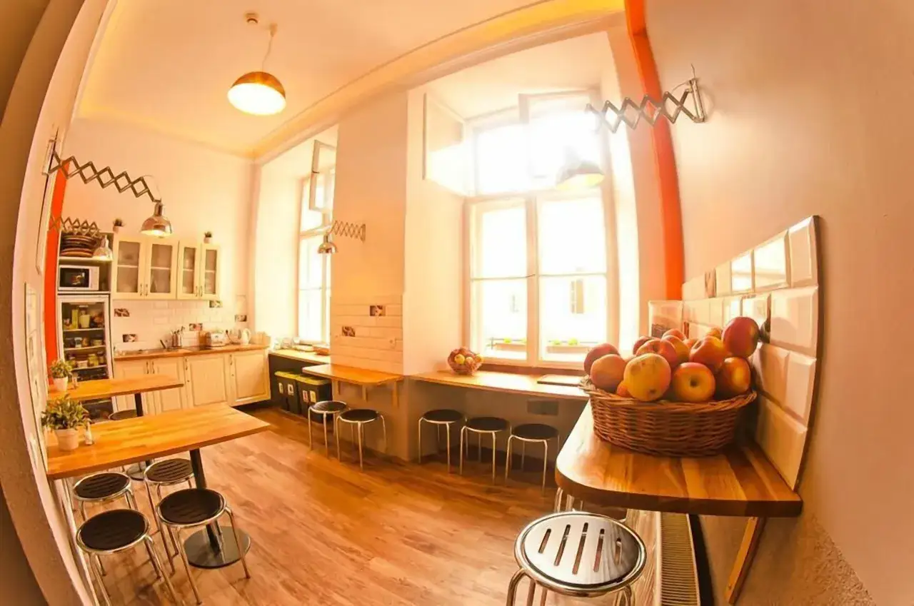 Wspólna kuchnia w hostelu, gdzie można dowiedzieć się, ile kosztuje nocleg w Krakowie. Na blacie koszyk z jabłkami.