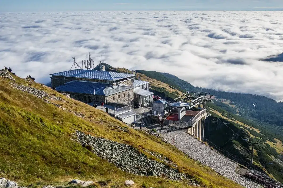 Widok na budynek g&oacute;rnej stacji kolejki na Kasprowy Wierch, otoczony morzem chmur.