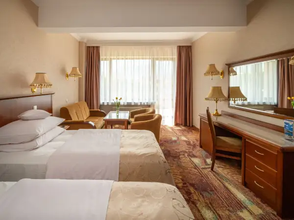 Pokój hotelowy z dwoma łóżkami, kanapą i biurkiem. Dowiedz się, ile kosztuje nocleg w hotelu Gołębiewski.