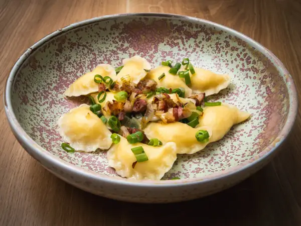 Pierogi z boczkiem i cebulką, danie z restauracji Bacówka, prezentowane na talerzu.