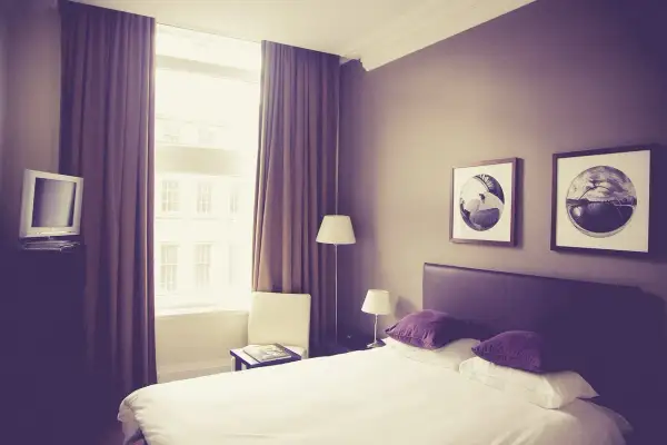 Pokój hotelowy z łóżkiem, oknem i telewizorem.
