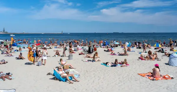 Tłum ludzi na plaży, opalanie, kąpiel w morzu. Zastanawiasz się, ile kosztuje nocleg nad morzem?