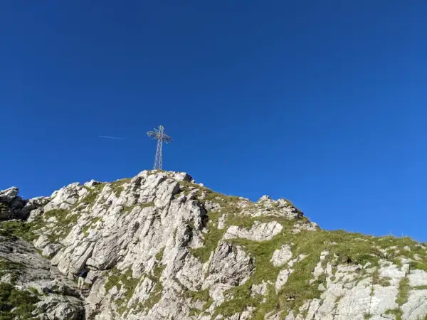 Krzyż na szczycie skalistego Giewontu na tle błękitnego nieba.